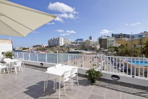 a balcony with tables and chairs and a view of a city at Cresta Beach Studios in St. Julianʼs