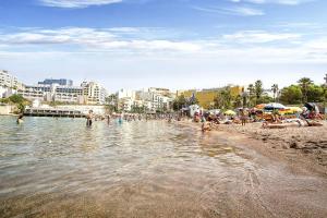 a beach with a bunch of people in the water at Cresta Beach Studios in St. Julianʼs