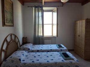 two beds in a bedroom with a window at Enjoy Sunset in Colle Massari