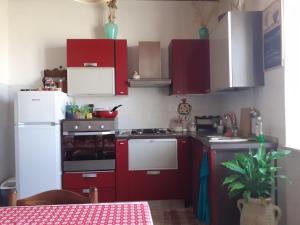 a kitchen with red cabinets and a white refrigerator at Enjoy Sunset in Colle Massari