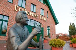 Eine Statue eines Mannes, der vor einem Gebäude sitzt. in der Unterkunft Etzhorner Krug in Oldenburg