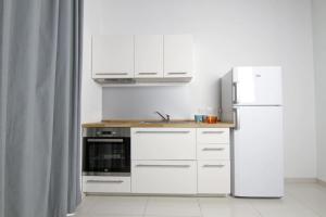 a kitchen with white cabinets and a refrigerator at Cresta Beach Studios in St. Julianʼs