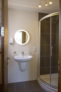 a bathroom with a sink and a shower and a mirror at Cresta Beach Studios in St. Julianʼs