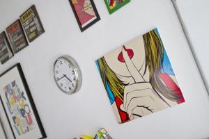 a clock on a wall with a picture of a woman at Cresta Beach Studios in St. Julianʼs