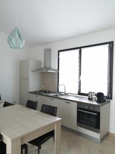 a kitchen with a table and a large window at Appartamento Monte Granatico 02 in SantʼAntìoco