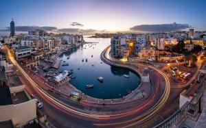 a city at night with a river and buildings at Cresta Beach Studios in St. Julianʼs