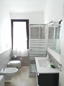 a white bathroom with a toilet and a sink at Appartamento Monte Granatico 02 in SantʼAntìoco