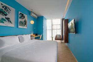 um quarto com uma cama branca e paredes azuis em Shenzhen Dongmen Colour Hotel em Shenzhen