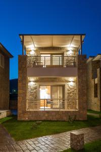 a large brick house with a balcony at night at Costa D' Ifesto in Agios Ioannis Kaspaka