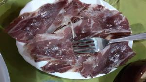 een bord vlees met een vork erop bij Agriturismo S'Armidda in Seùlo