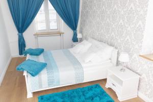 a bedroom with a white bed with blue curtains and a window at Apartamenty Hexus - Świdnicka - Wrocław centrum Rynek in Wrocław