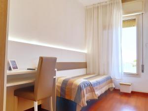 a bedroom with a bed and a desk and a window at Hotel Telenia in Lido di Jesolo
