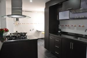 a kitchen with black cabinets and a sink at Apartamentos Plaza Modelia in Bogotá +27 photos