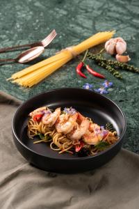 a bowl of pasta with shrimp on a table with chopsticks at MeStyle Museum Hotel in Bangkok