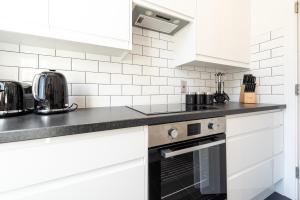 una cucina con armadietti bianchi e ripiani neri di Hyde Park Apartment (SS1) a Londra