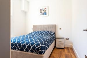 a bedroom with a bed with a blue and white comforter at Hyde Park Apartment (SS1) in London