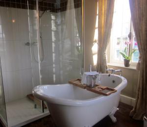 a white bath tub in a bathroom with a shower at Le Manoir de Herouville in Litteau