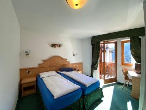 a bedroom with a bed and a desk and a window at Hotel Camoscio in Rocca Pietore