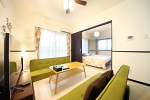sala de estar con sofá verde y cama en EX Itoman Apartment 803, en Itoman