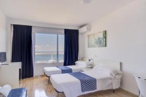 Cette chambre comprend 2 lits et une fenêtre. dans l'établissement Las Palomas Apartments Econotels, à Palma Nova