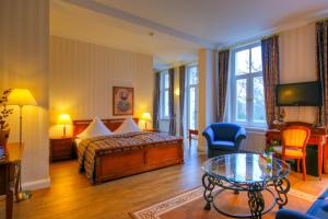ヴァーネミュンデにあるKurparkHotel Warnemündeのベッドとテーブルが備わるホテルルームです。
