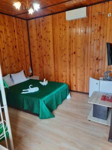 Habitación con una cama verde en una pared de madera. en Madlen Cottages, en Adler