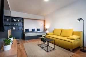 a living room with a yellow couch and a bed at FLEXIHOME sk - Bellova - Brand New - Neftflix - Private Parking in Liptovský Mikuláš