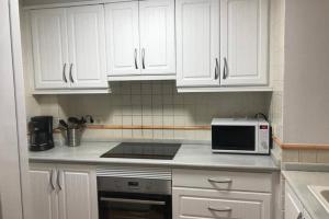 een keuken met witte kasten en een magnetron bij MET&GOLF OLIVA NOVA BEACH in Oliva