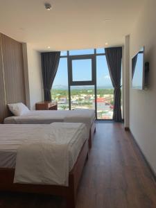 a hotel room with two beds and a large window at Hoang Sa Bai Dai Hotel in Cam Ranh