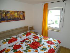 a bedroom with a bed with a floral comforter and a window at Ferienwohnung Hofstatt in Lalling