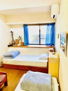 新島村にあるゲストハウスイケタのベッドルーム1室(ベッド2台、青いカーテン付きの窓付)
