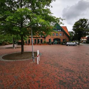 ein Backsteinparkplatz mit einem Baum vor einem Gebäude in der Unterkunft Etzhorner Krug in Oldenburg