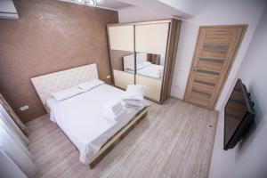 ein Schlafzimmer mit einem Bett, einem Spiegel und einem TV in der Unterkunft Moonlight Apartments in Mamaia