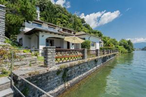 a house by the water with an umbrella at Villa Bianca - Front Lake Pool by Rent All Como in Sala Comacina +80 photos