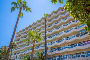 un grand hôtel avec des palmiers devant lui dans l'établissement Las Palomas Apartments Econotels, à Palma Nova