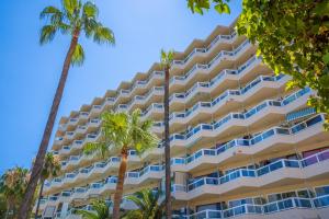 a large hotel with palm trees in front of it at Las Palomas Apartments Econotels in Palmanova