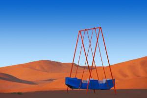 a swing in the middle of a desert at Dunhuang Vivian Desert Camping in Dunhuang
