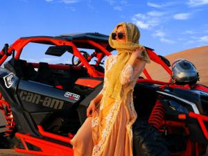a woman in a dress standing next to a atv in the desert at Dunhuang Vivian Desert Camping in Dunhuang