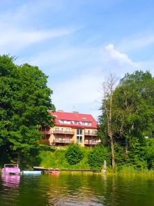 a building on the side of a lake with boats at Wiking in Kretowiny