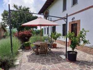 un patio con mesa y sombrilla en Cascina Volpona, en Case Bruciate