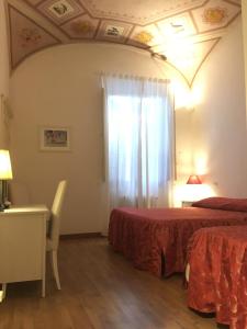 シエナにあるRelais La Corte dei Cavalieriのベッド2台、デスク、窓が備わる客室です。