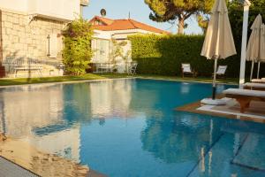 a swimming pool with an umbrella next to a house at Gobene Alacati in Alaçatı