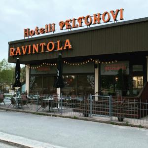 un restaurante con mesas y sombrillas frente a él en Hotelli Peltohovi, en Kiuruvesi