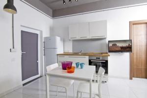 a white kitchen with a white table and chairs at Cresta Beach Studios in St. Julianʼs