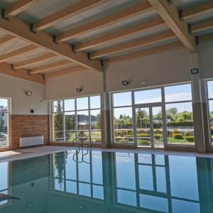 an indoor pool with windows and a ceiling with beams at Hotel ***NAT Sarbinowo in Sarbinowo