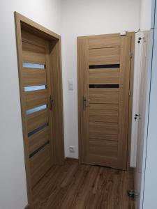 Duas portas de madeira num quarto com pisos de madeira em Apartamenty Lawendowy Zakątek 4 em Opole