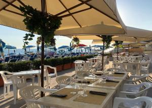a restaurant with white tables and chairs and an umbrella at Hotel Rex in Livorno