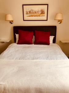 a bedroom with a white bed with two red pillows at The Barford Inn in Salisbury