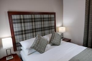 a bedroom with a white bed with two pillows at Carrbridge Hotel in Carrbridge