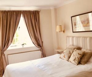 a bedroom with a white bed and a window at The Barford Inn in Salisbury